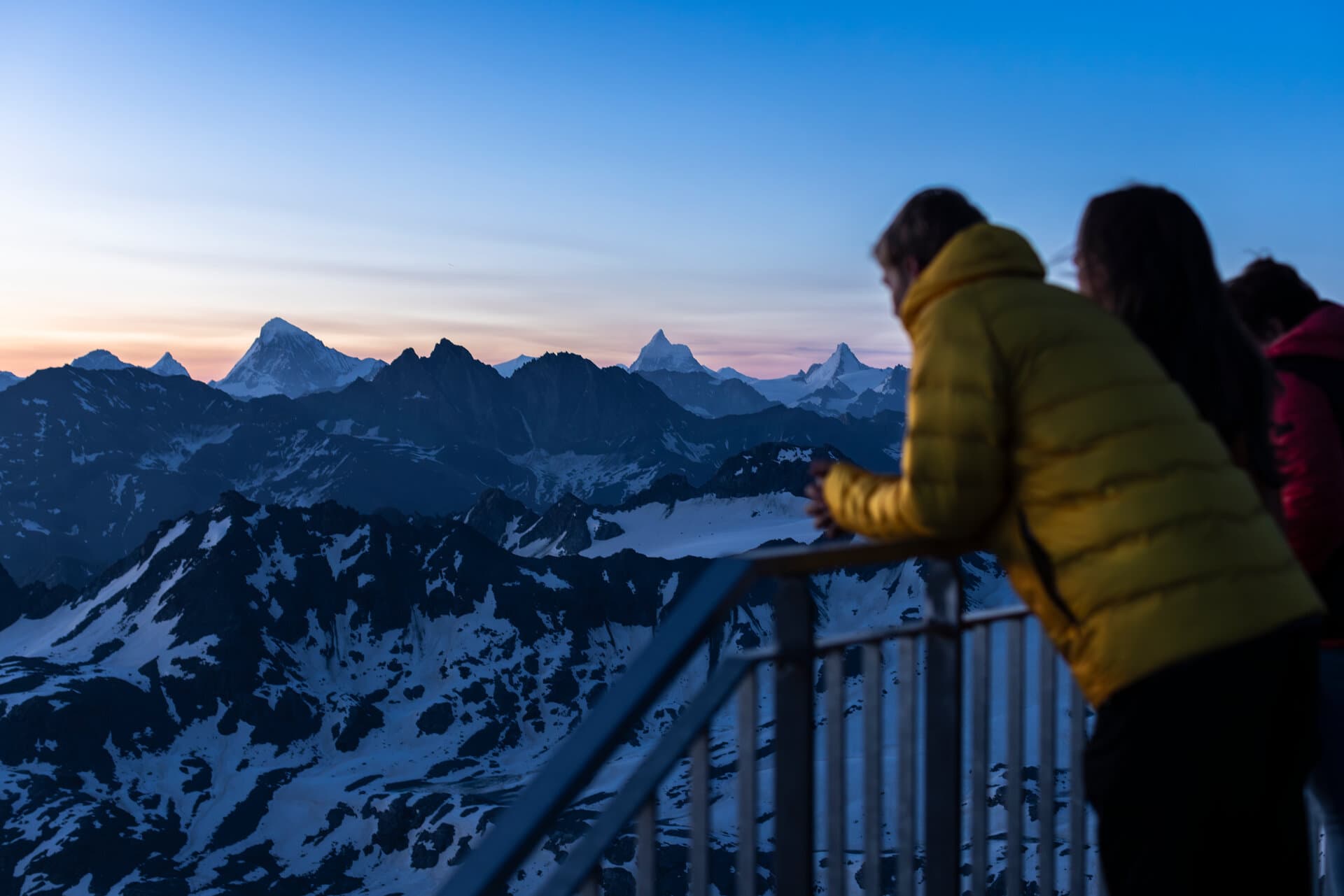 Persone osservano le cime innevate all’alba